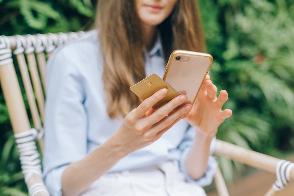 Woman using a smartphone while holding a credit card for a mobile purchase
